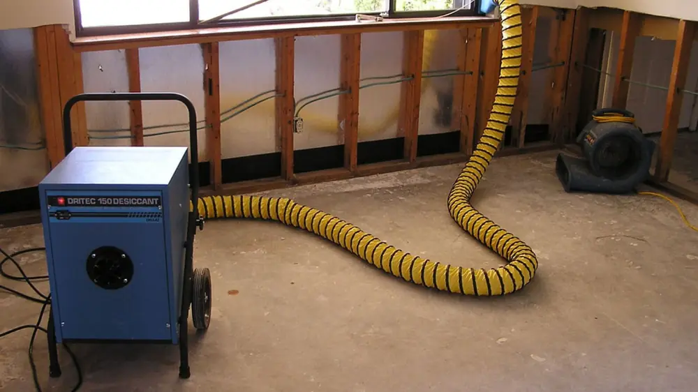 Opened wall cavity with a dehumidifier and flexible duct drying the framing