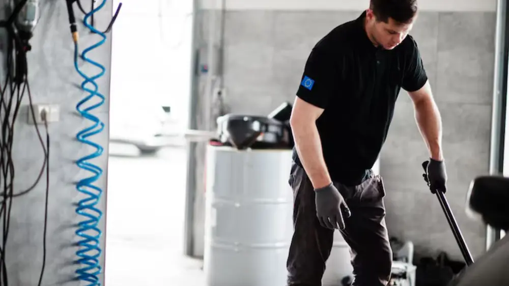 Worker in black clothing clearing water from a flooded basement floor