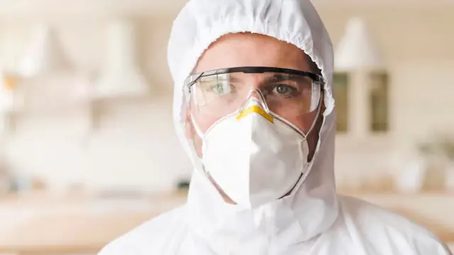 Worker wearing a hood, goggles and respirator mask